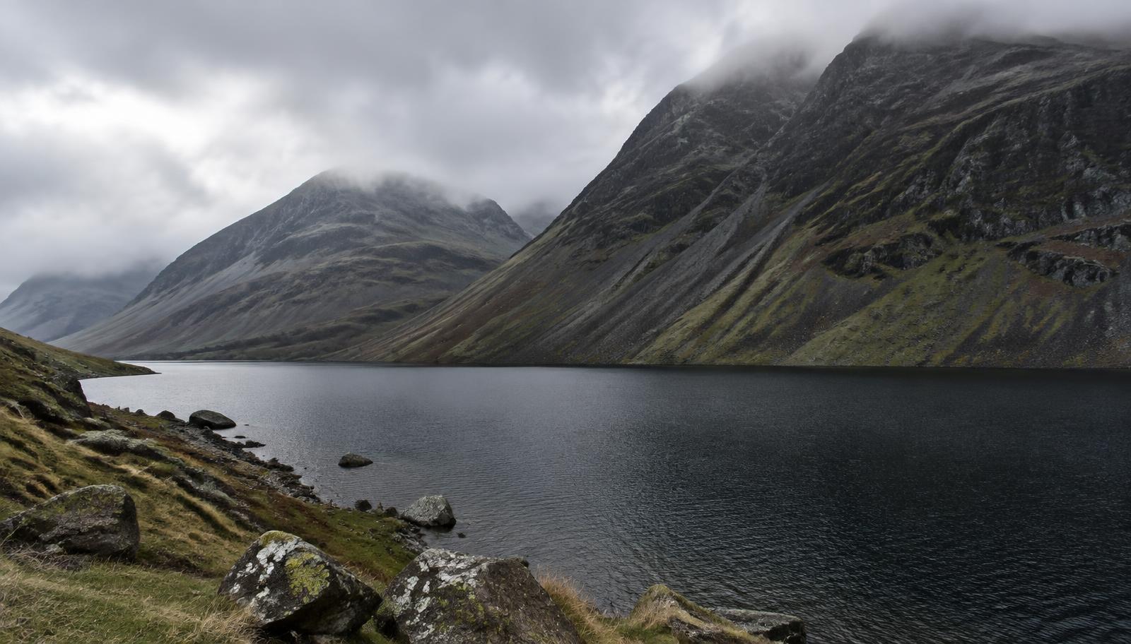 Wastwater beneath steep scree slopes and cloud-topped fells in Wasdale
